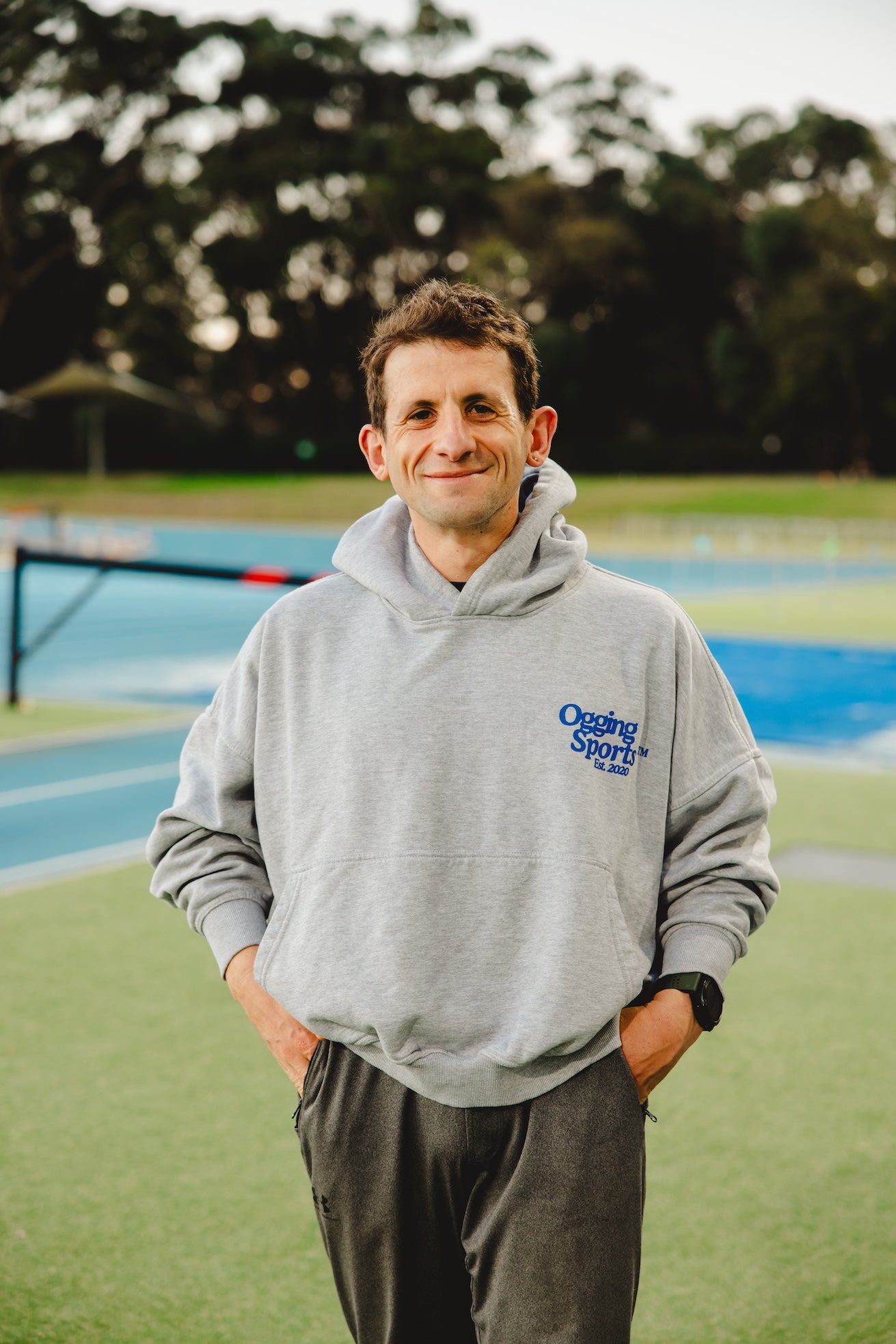 Agostino wearing a gray hoodie with a logo on a sports field