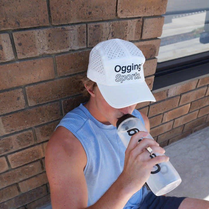Person taking a break from exercise, leaning against a wall with a water bottle.