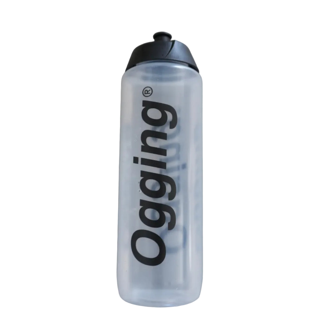 Clear water bottle with black lid and 'Ogging' branding on a gray tiled floor.